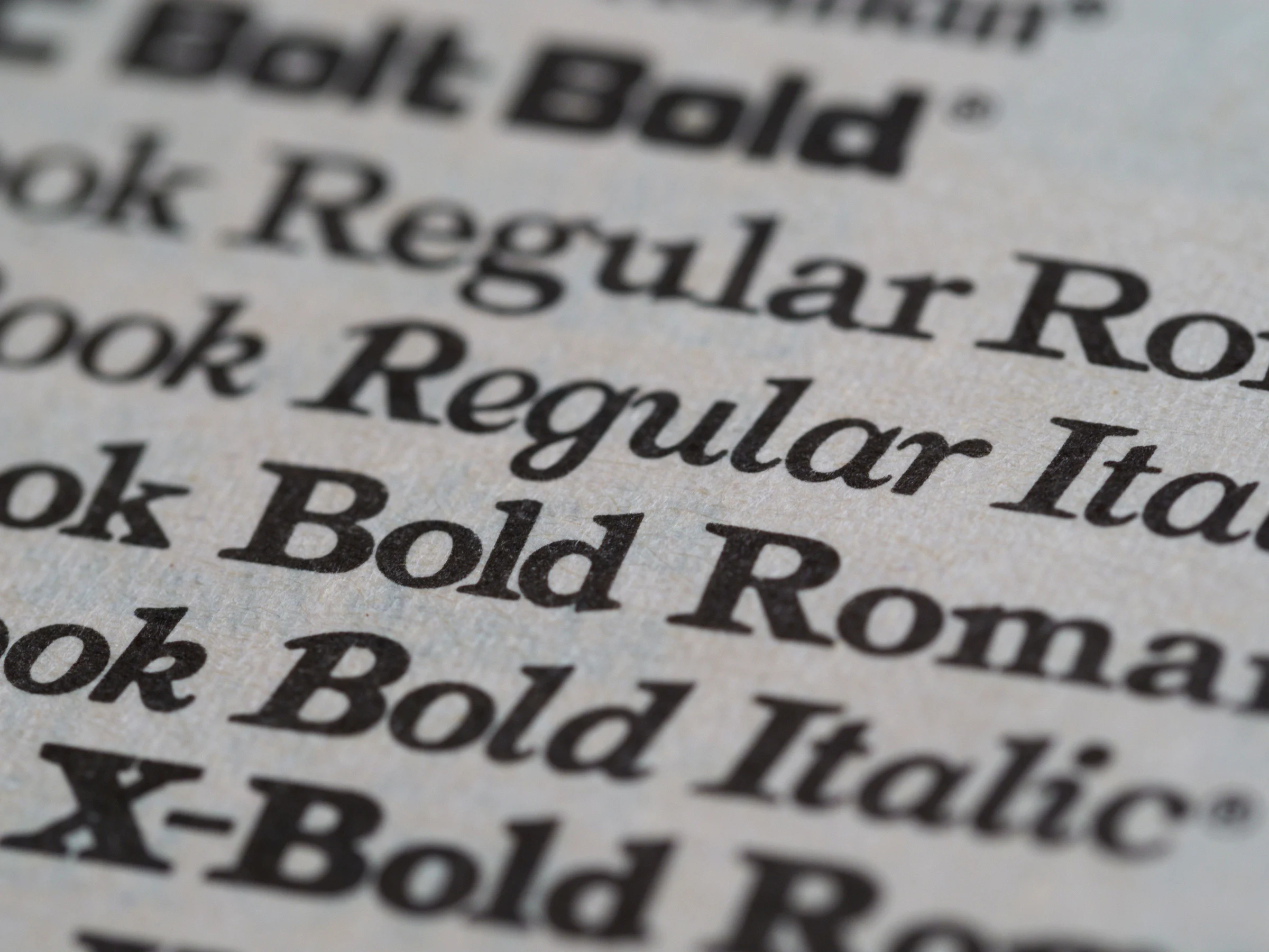 Cận cảnh các kiểu chữ Bold, Regular và Italic được in trên giấy, minh họa weight và style của phông chữ.