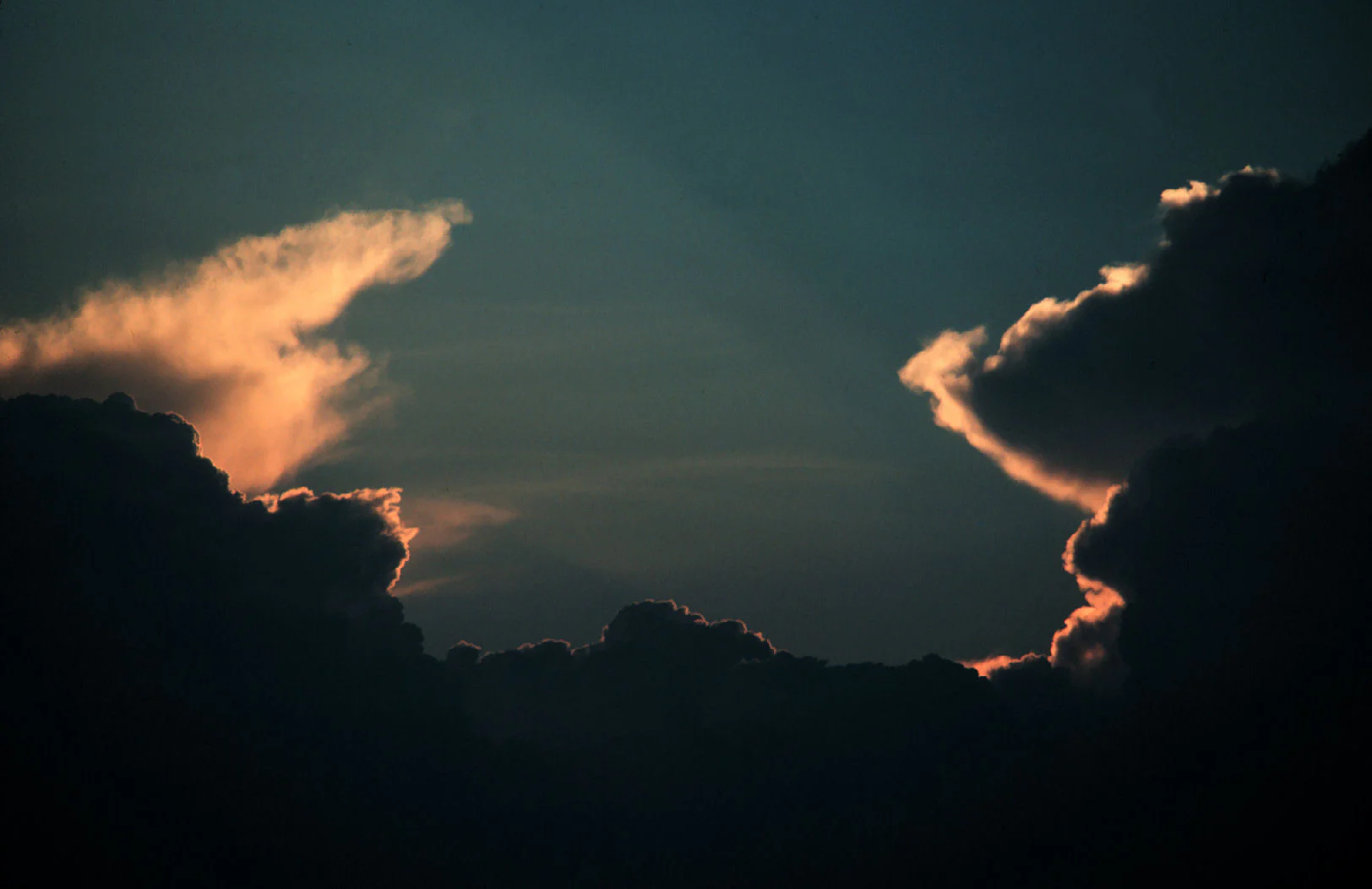 Hai khối cumulonimbus tối có viền sáng cam lúc hoàng hôn