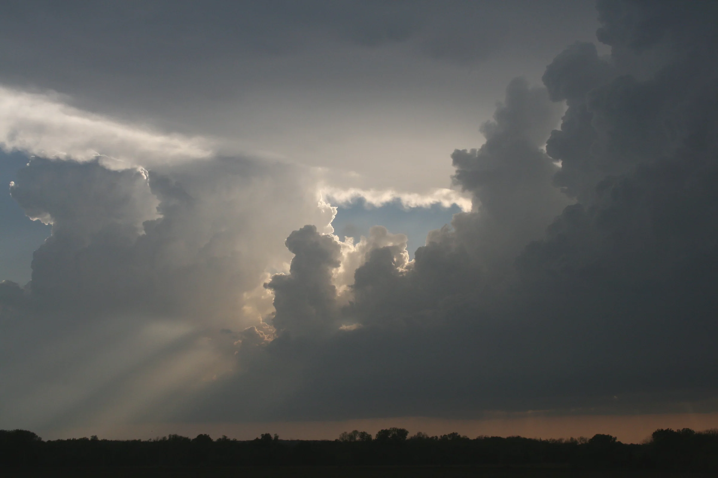 Mây anvil phủ trên các cột cumulonimbus với tia sáng xuyên qua