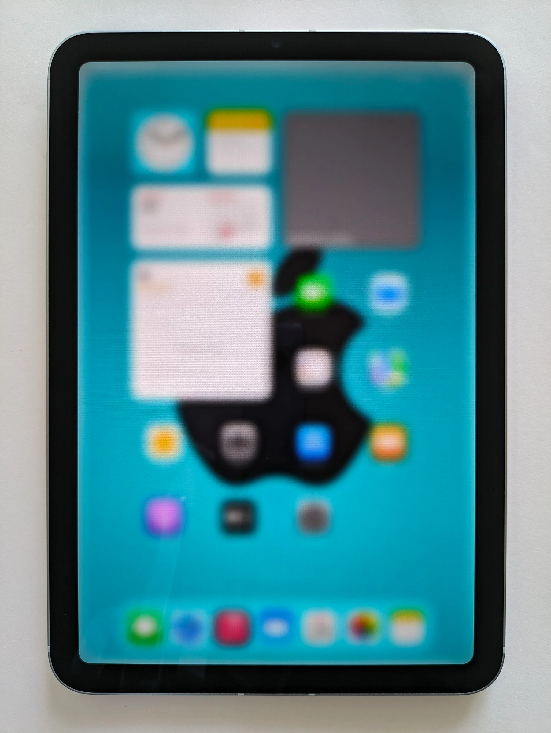 Một chiếc iPad dựng đứng hiển thị màn hình chính iPadOS với các biểu tượng đã được làm mờ